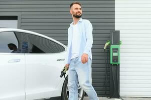 hombre en pie por su eléctrico coche foto