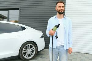 hombre en pie por su eléctrico coche foto