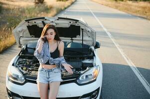 Young sexy woman with broken car calling on the cell phone. photo