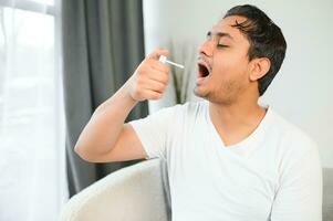 An Indian man has the flu. A man uses a throat spray. photo