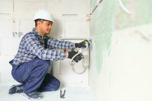 Indian plumber installing water equipment - meter, filter and pressure reducer photo