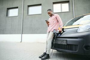 African American man charging his electric car. photo