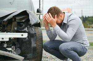 A frustrated man near a broken car. Grabbed my head realizing the damage is serious, the car is beyond repair photo