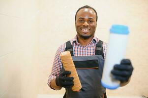 African American plumber holding new and used water filters photo