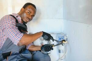 African American Plumber installs or change water filter. Replacement aqua filter photo