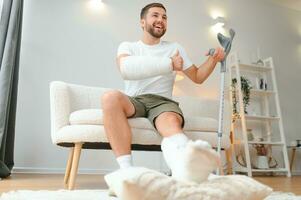 man recovery from accident fracture broken bone injury with leg splints in cast neck splints collar arm splints sling support arm in living room. Social security and health insurance concept photo