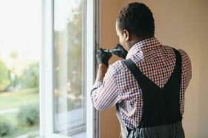 Close-up Of Young African Handyman In Uniform Installing Window photo