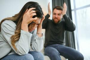 Emotional man gesturing and shouting at his wife, young couple having quarrel at home. Domestic abuse concept photo