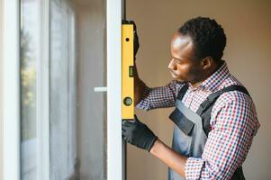 Close-up Of Young African Handyman In Uniform Installing Window photo