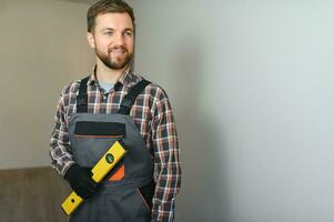 Portrait of positive, handsome young male builder while working at construction site. photo