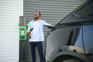 africano americano hombre cargando su eléctrico coche. foto