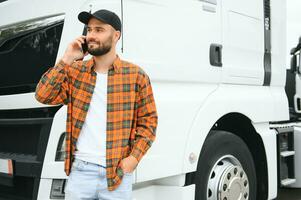 Portrait of young bearded trucker standing by his truck vehicle. Transportation service. Truck driver job photo