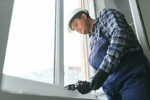 Indian service man installing window with screwdriver photo