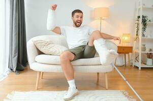 Man with multiple physical limb and body injuries recovers after accident. Happy guy having fun at home photo