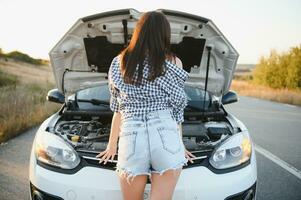 sexy girl stand by the broken car and don't know what to do. Rear view. photo