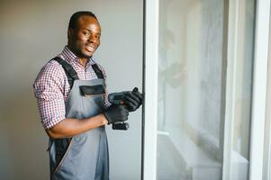 Close-up Of Young African Handyman In Uniform Installing Window photo