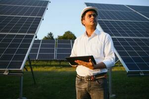 retrato de joven indio masculino ingeniero en pie cerca solar paneles, con claro azul cielo fondo, renovable y limpiar energía. habilidad India, Copiar espacio foto