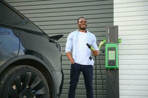 African American man charging his electric car. photo