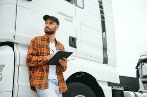 Male driver with clipboard near big truck outdoors photo
