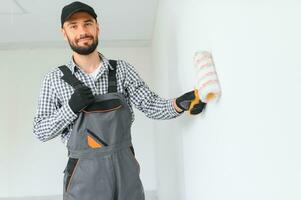 Young worker painting wall in room. photo