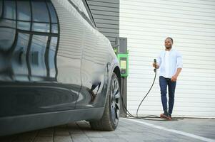 Man charging his electric car at charge station photo