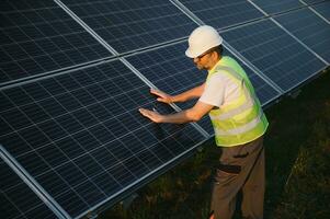 Side view of male worker installing solar modules and support structures of photovoltaic solar array. photo