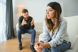 Emotional man gesturing and shouting at his wife, young couple having quarrel at home. Domestic abuse concept photo