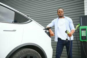 Man Plugging In Electric Car Outside Office In Car Park Charging photo