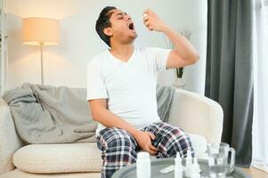 un indio hombre tiene el gripe. un hombre usos un garganta rociar. foto