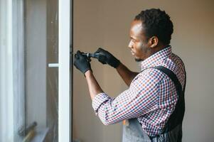 Close-up Of Young African Handyman In Uniform Installing Window photo