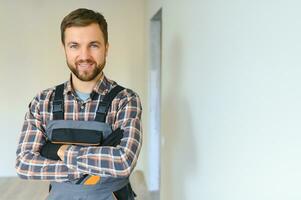 Portrait of a confident repairman with beard standing in empty apartment photo