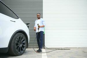 African American man charging his electric car. photo