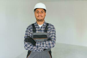 profession, construction and building - happy smiling indian worker or builder in helmet over grey background. photo