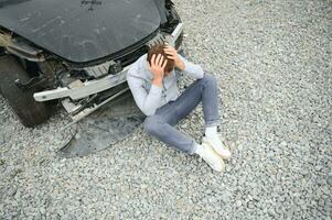 Young man driver in car accident near broken car on the road after a car accident photo