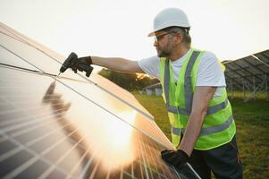 Side view of male worker installing solar modules and support structures of photovoltaic solar array. photo