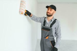 joven profesional trabajador en uniforme en pie con pintar rodillo. foto