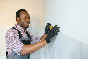 African American Worker installing wall tile with vacuum holder indoors photo