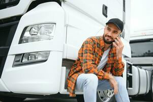 Man trucker talking on the phone by his white truck photo