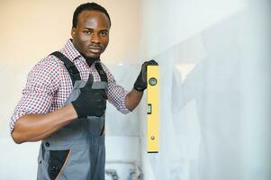 African American Worker installing wall tile with vacuum holder indoors photo