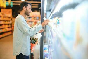 Portrait of happy handsome young Indian at grocery shop or supermarket. photo