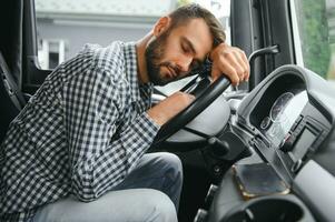 Man trucker tired driving in a cabin of his truck photo