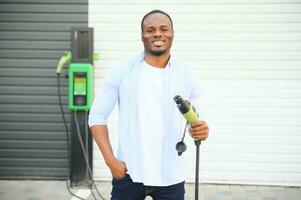 africano americano hombre cargando su eléctrico coche. foto