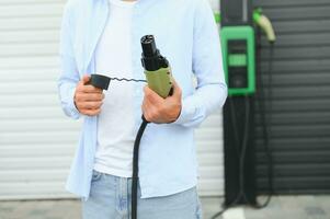 Close Up Of Hand Holding Power Cable For Environmentally Friendly Zero Emission Electric Car photo