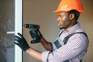 Close-up Of Young African Handyman In Uniform Installing Window photo