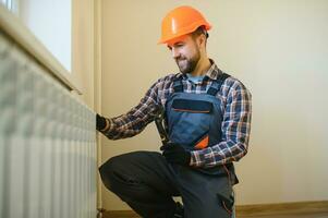 Plumber man is blocking repairs radiators of heating battery in apartment tap photo