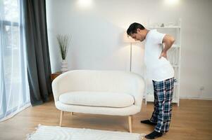 Portrait of Indian guy backache, holding spine with hand photo