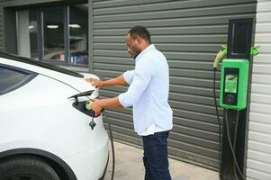 Man Plugging In Electric Car Outside Office In Car Park Charging photo