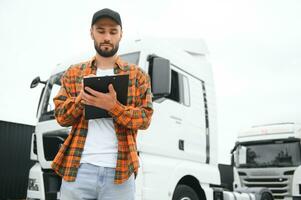 Male driver with clipboard near big truck outdoors photo