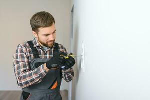 Electrician installs decorative frame on electric and TV sockets photo