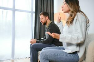 hermosa Pareja es sentado espalda a espalda en el sofá mientras teniendo un pelea foto